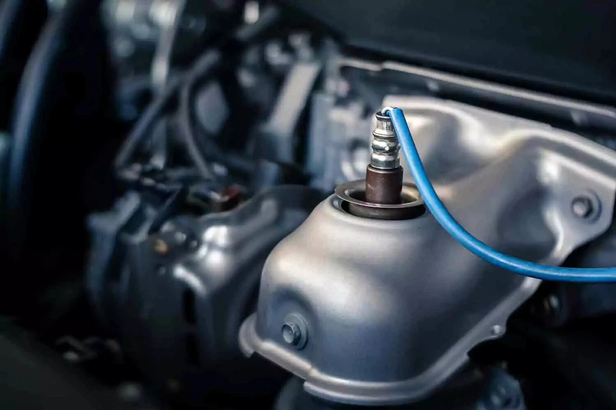A close-up view of the upstream oxygen sensor of a new vehicle. The sensor is mounted at the top of the exhaust manifold.
