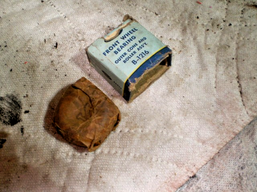 Small brown metal cone with worn white label reading “Front Wheel Bearing Outer Cone B-1216 Made in USA VTG” on fabric.
