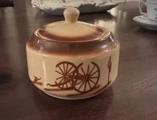A hand-painted wagon wheel Blue Ridge China lidded jar with a Western motif.