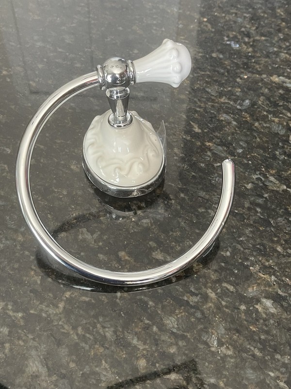 wall-mounted towel ring with a chrome finish and white ceramic elements.