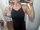 Black evening maxi halter dress with V-neckline and thin straps, shown on mannequin in front of mirror.
