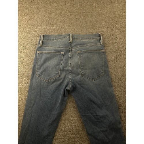 Back view of Frame Jeans women 25 with frayed hems, two pockets, and belt loops on beige fabric surface.