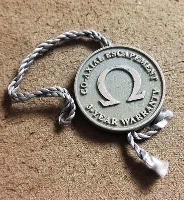 Omega grauer Kunststoffanhänger ''Co-Axial Hemmung'' neuwertig Zustand