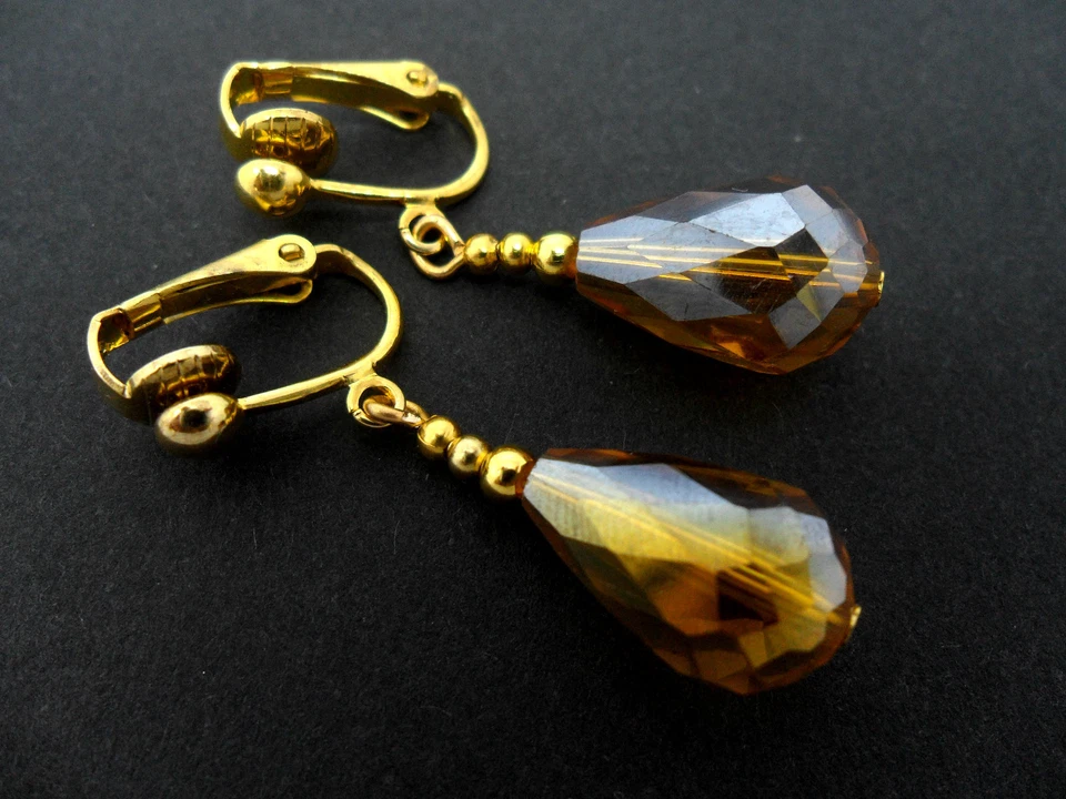 A PAIR OF GOLD TONE AMBER GLASS CRYSTAL TEARDROP CLIP ON EARRINGS. NEW. - Image 1 of 1