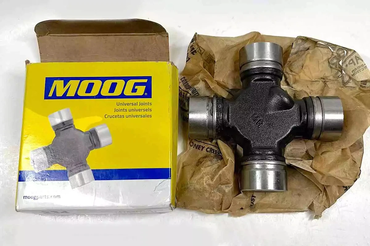 A MOOG Non-Greaseable U-Joint with its original packaging, displayed on a white work surface.