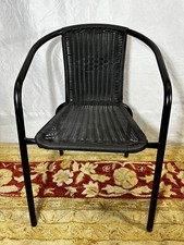 Silla de exterior de ratán apilable negra en buen estado usada, algunos defectos