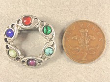 Celtic style silver pin brooch featuring six gemstones set in a fretted circlet