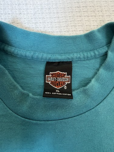 Blue Harley-Davidson men’s XL T-shirt with black tag showing logo, made in USA.