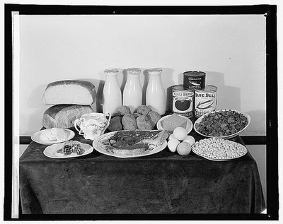 Photo:Still Life Table of Bread Milk Eggs Canned Goods and Food Staples