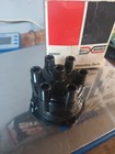 Black Borg-Warner 6-cyl conventional distributor cap with eight spark plugs, made in USA, shown in front of a red box.