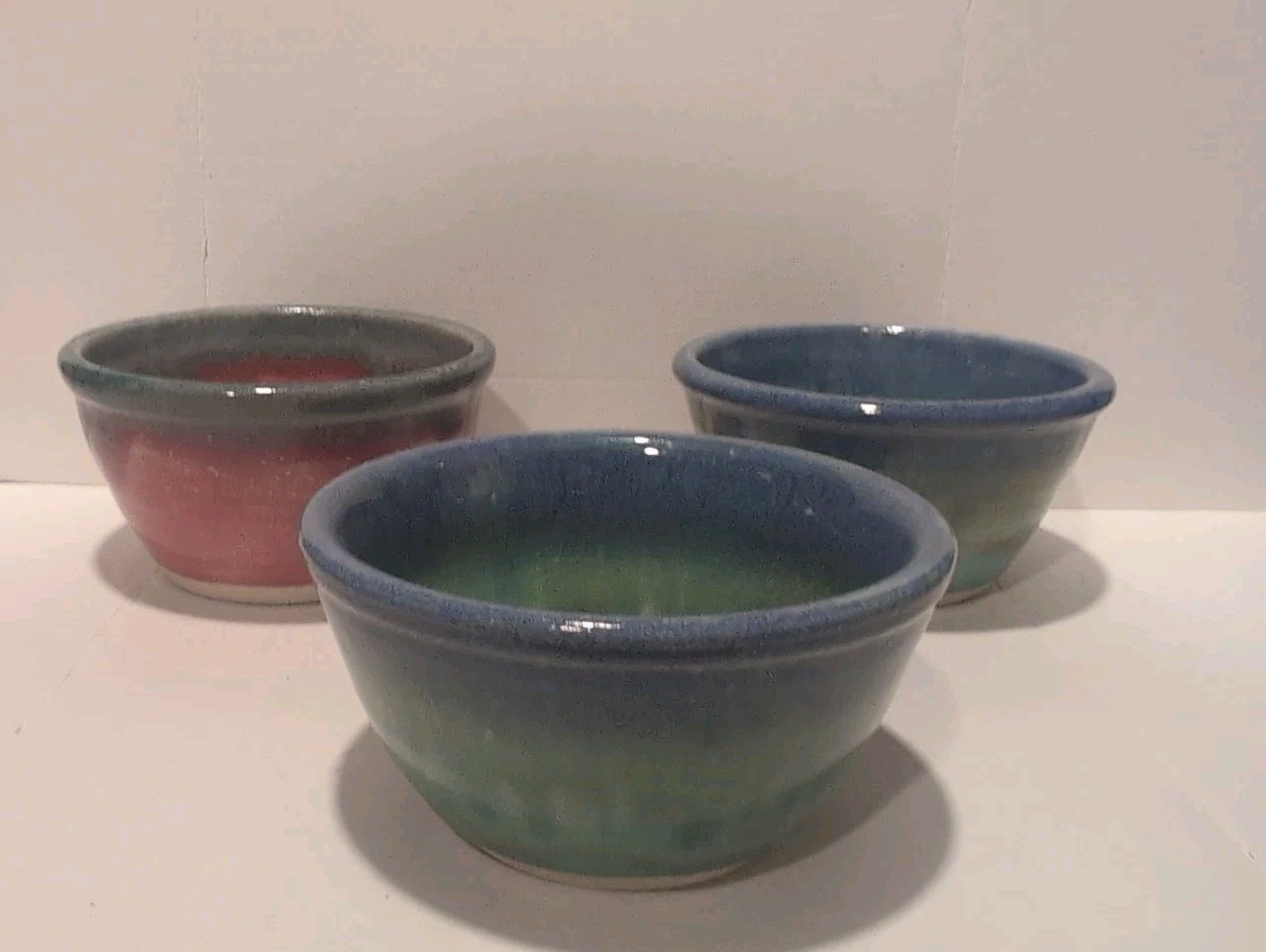 Set of three small studio pottery bowls with blue-green drip glaze, signed Lisa.