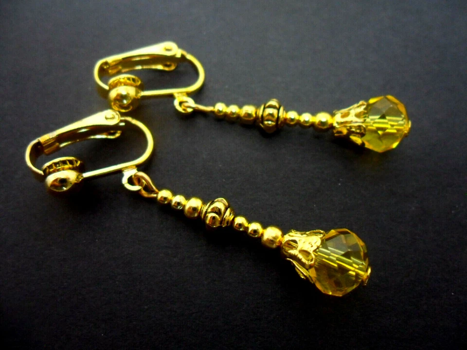 A PAIR OF GOLD TONE YELLOW AMBER GLASS CRYSTAL CLIP ON EARRINGS. NEW. - Image 1 of 1