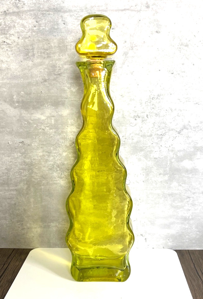 A swirling olive-green genie bottle decanter in pure MCM style — it looks like it belongs on a Bond villain's sideboard.