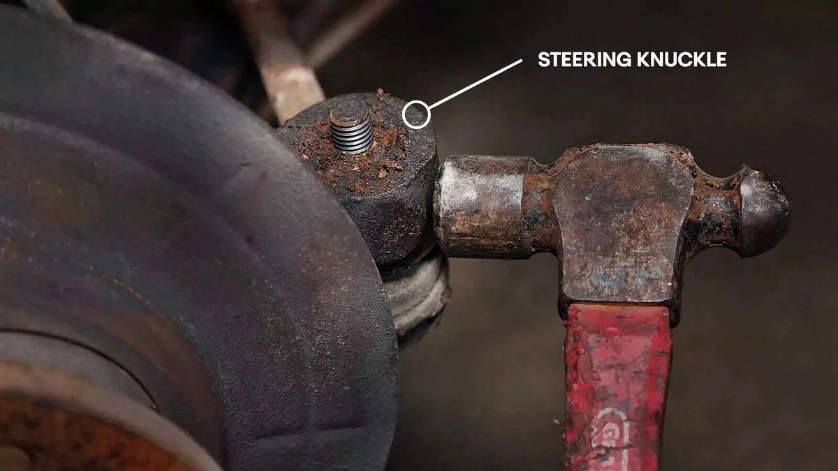 An annotated photograph showing a ball peen hammer meeting the steering knuckle.