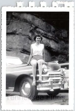 Black & White Photo Of A Lovely Lady In Shorts Setting Of The Hood Of 50s Car