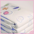 White ABU Cushies plastic back with pastel bear, bird, and heart graphic on blue background, folded on pink surface.