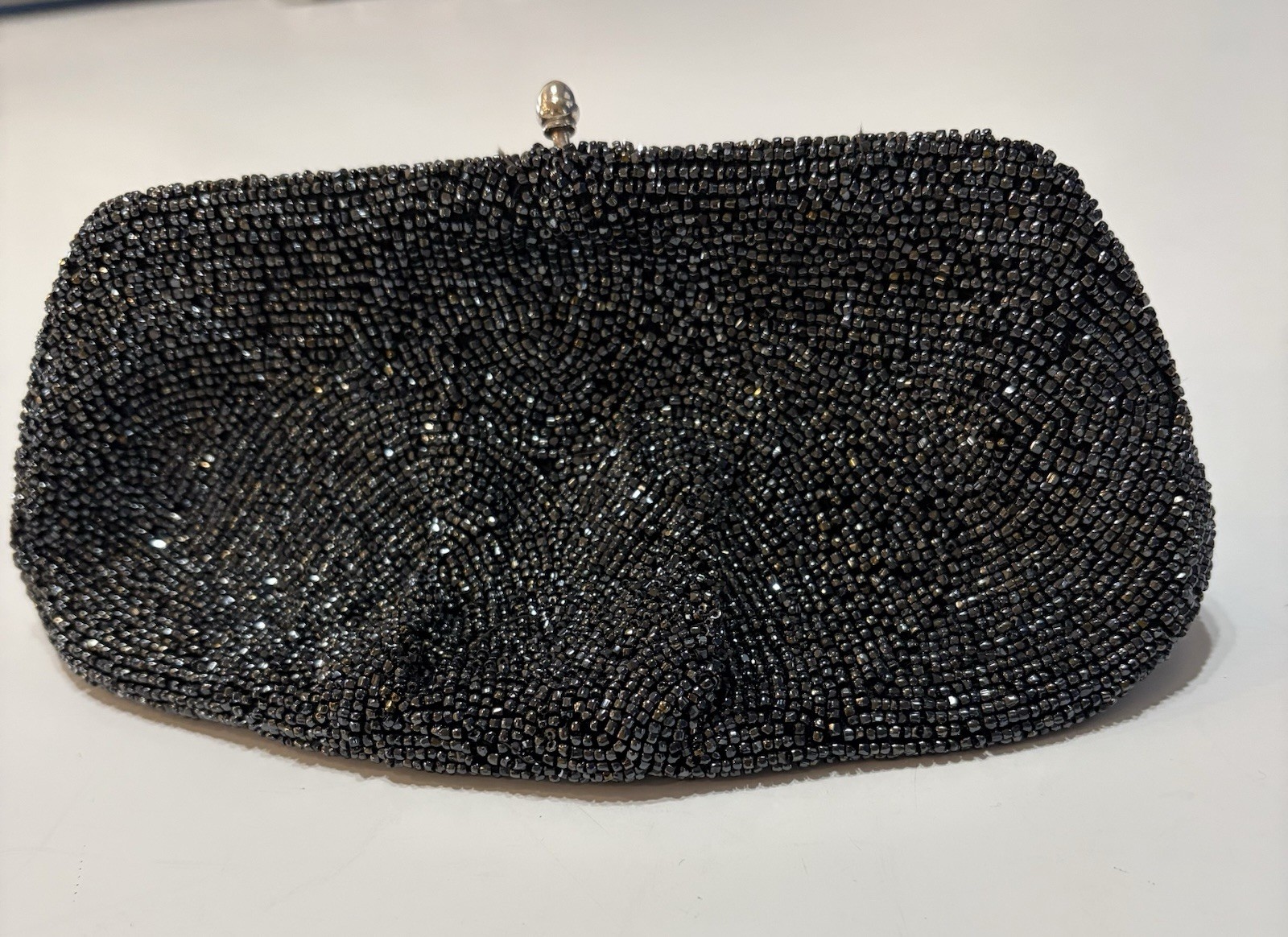 Black beaded kiss-lock evening clutch purse on a white background.