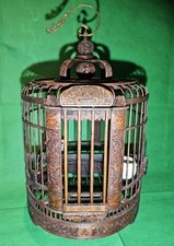 Vintage Chinese bamboo birdcage featuring intricate carvings, feeding cups.