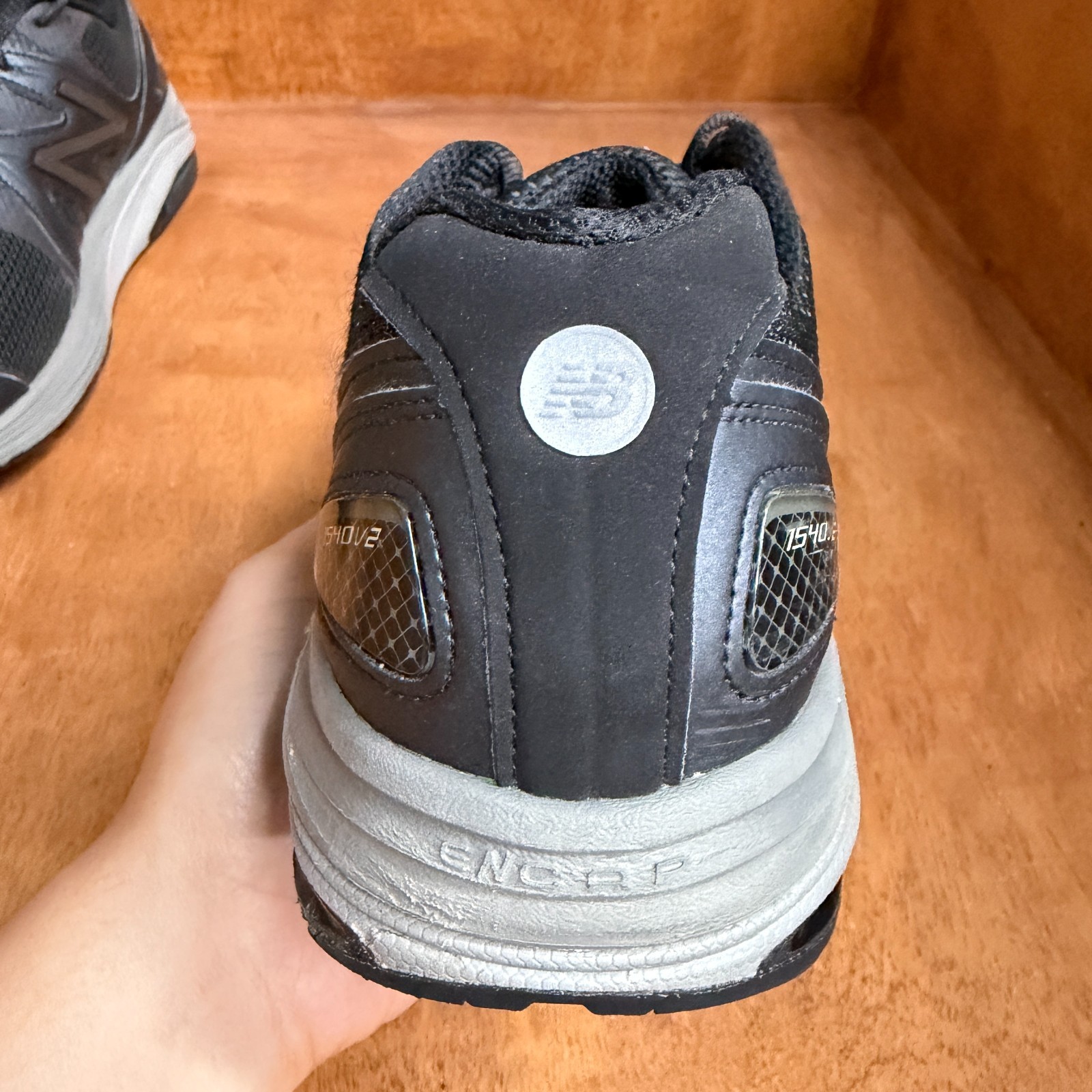 Black and gray New Balance 1540V2 men’s running shoes with silver logo, mesh upper, and rubber sole, made in USA.
