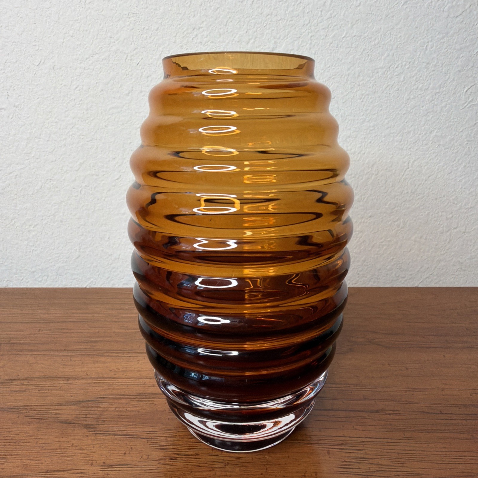 Deep amber ribbed round glass vanity jar on a white background.