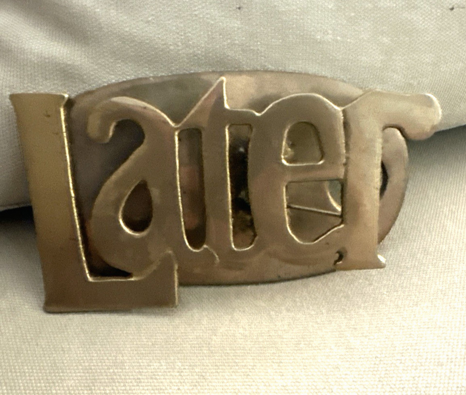 Solid brass paper clip/holder engraved with 'LATER' — the procrastinator's desk accessory of dreams.