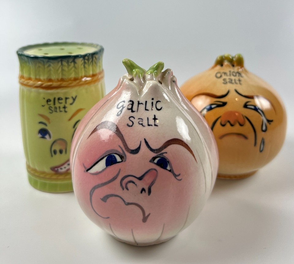 A charming set of mid-century anthropomorphic veggie salt shakers — garlic, onion, and celery with little faces, the kind of kitsch that disappears fast at estate sales.