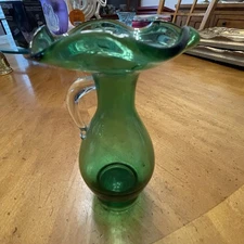 Vintage Hand Blown green glass pitcher vase with ruffled rim and clear handle.