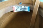 Brown hat with blue and red New York Paris label reading “Feather Classic” and “100% Wool” inside the cream lining.