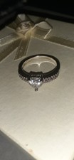 solitaire engagement ring with a heart-shaped center stone and pavé accents on t
