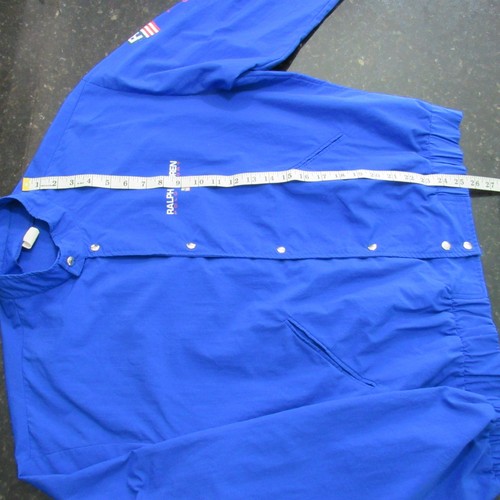 Blue Vtg 90s Polo Sport Ralph Lauren jacket with long sleeves, shown flat with measuring tape across the chest.