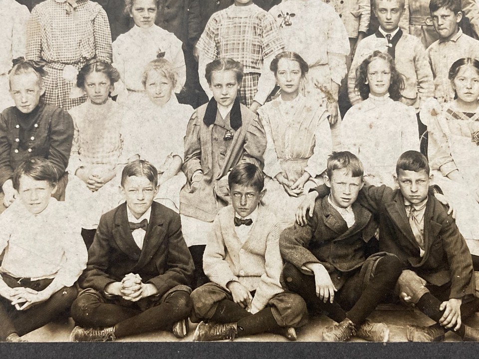 A genuine ~110-year-old photograph of eerily stiff-faced schoolchildren that radiates cabinet-of-curiosities energy — instant conversation piece on any dark-aesthetic shelf.