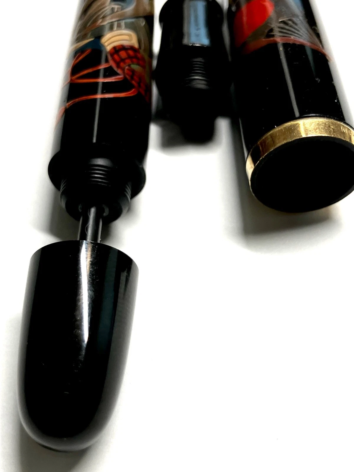 Black vintage ink shut off fountain pen with gold knob, surrounded by red and black floral haruama design on body.