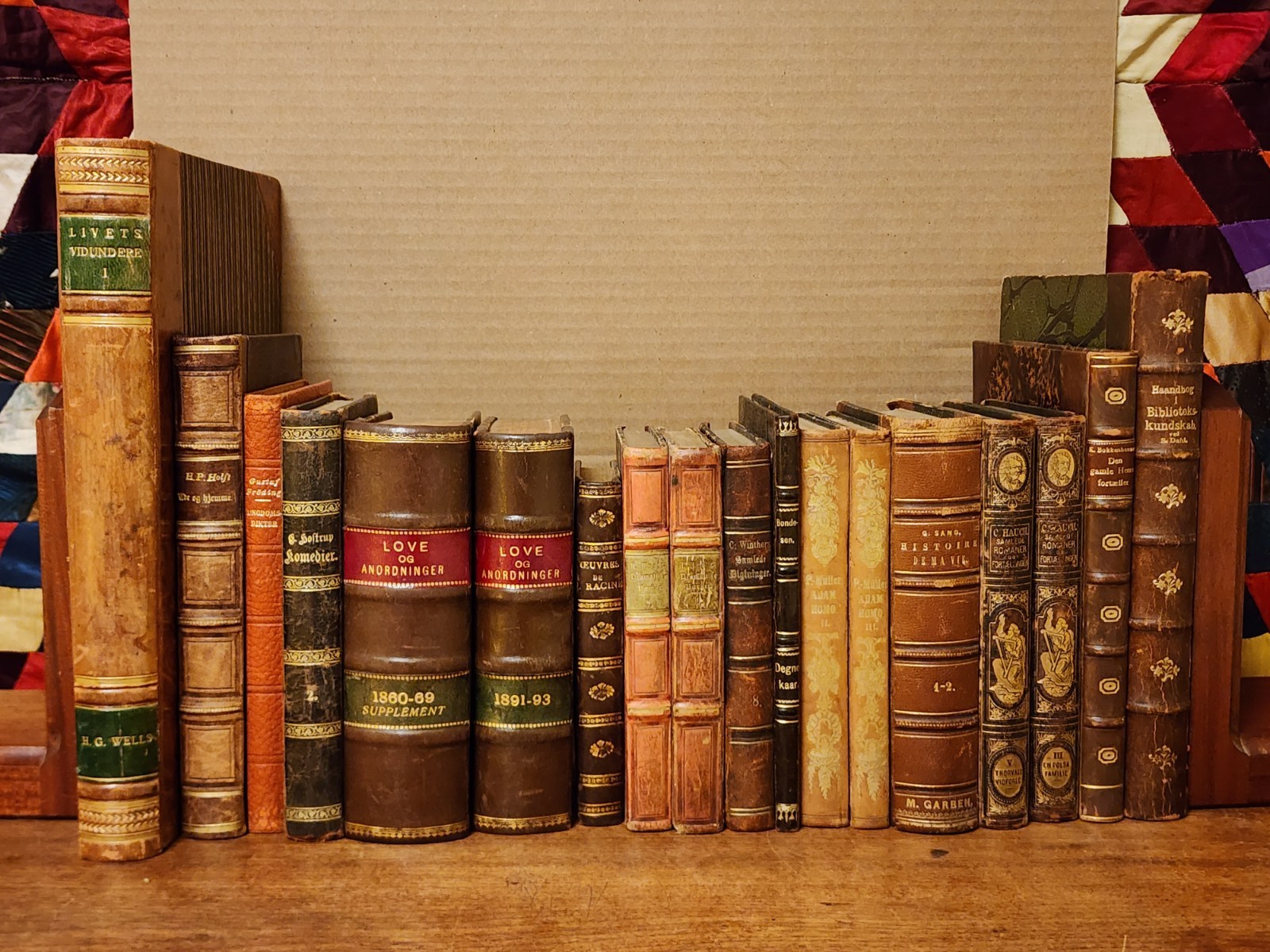 Stack of eighteen antique leather-bound books in varying sizes and worn leather colors, spines facing outward.