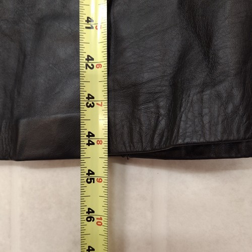 Black leather trench coat with red and beige shoulder pads, measuring tape along the length on a light background.