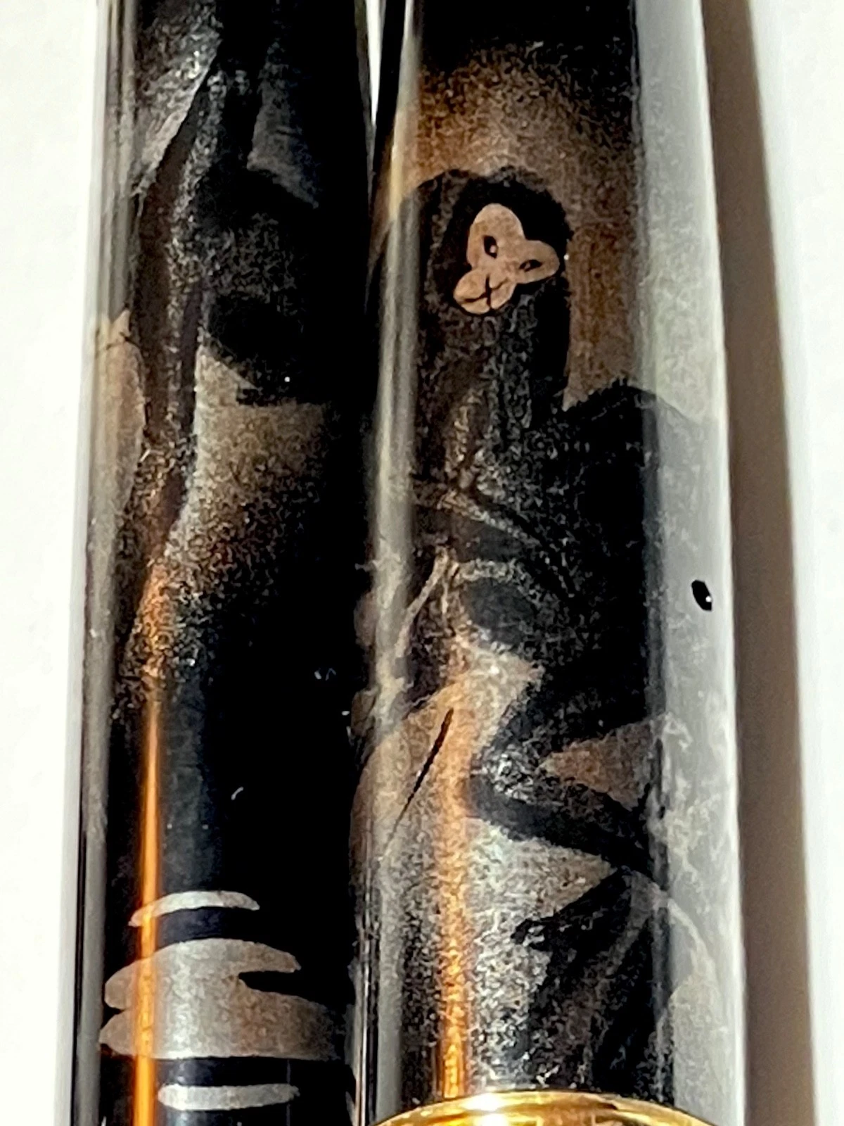 Black vintage fountain pen with gold ink, featuring faint monkey figure and gold starburst design on textured barrel.