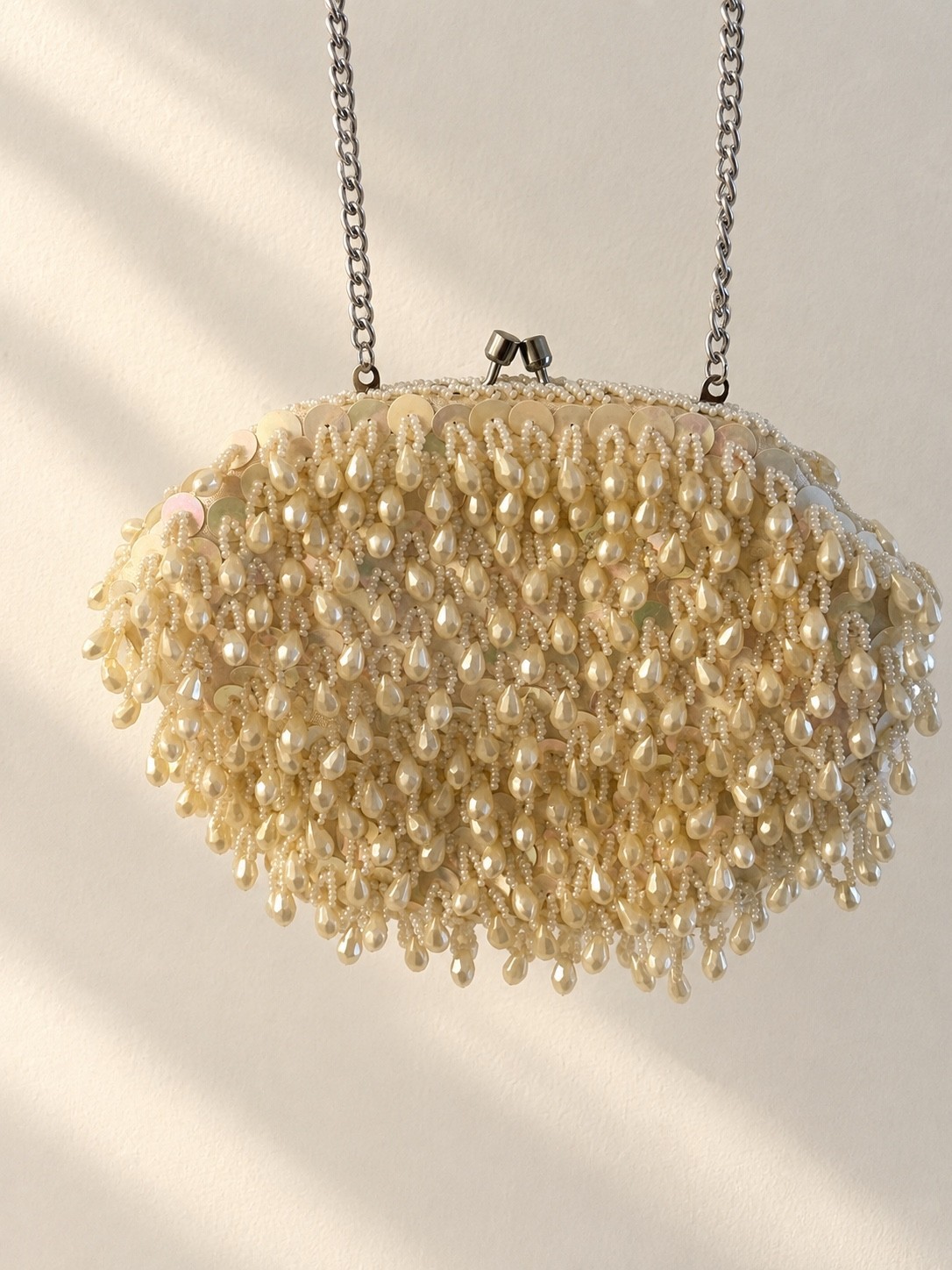 Ivory pearlescent sequin and fringe beaded evening clutch on a white background.