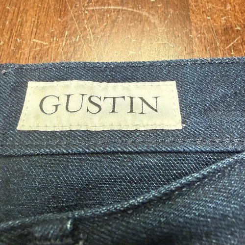 Dark blue denim fabric with white tag reading “GUSTIN” and size 30x29, made in USA.