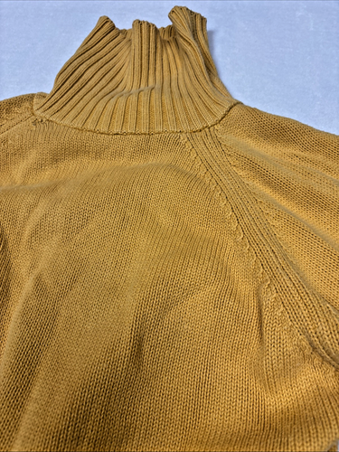 Mustard gold knit pullover sweater with long sleeves, high ribbed turtleneck, and visible stitching on the back.