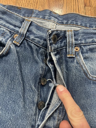 Vintage Levi’s 501XX blue denim with silver rivets, button closure, and “Made in U.S.A.” tag on waistband.
