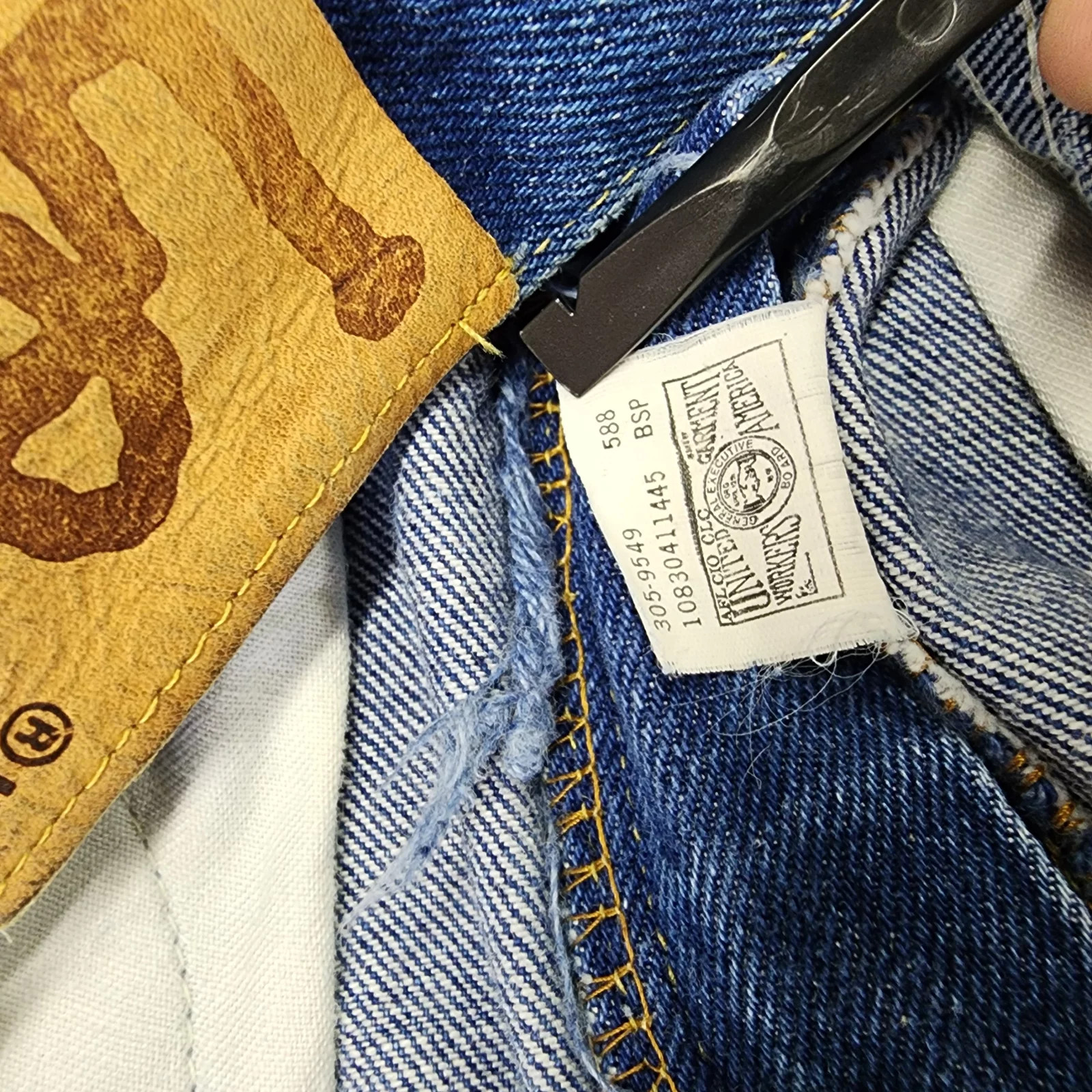 Vintage blue denim high-rise straight leg Lee jeans with black tag showing size 12 W26 L33 and yellow stitched pocket detail.
