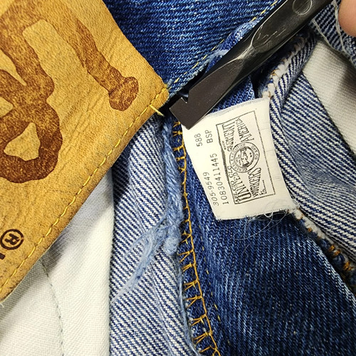 Vintage blue denim high-rise straight leg Lee jeans with black tag showing size 12 W26 L33 and yellow stitched pocket detail.