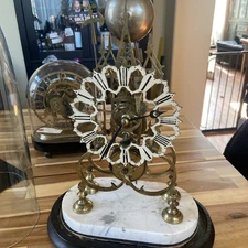 19th-century French skeleton clock under a glass dome.