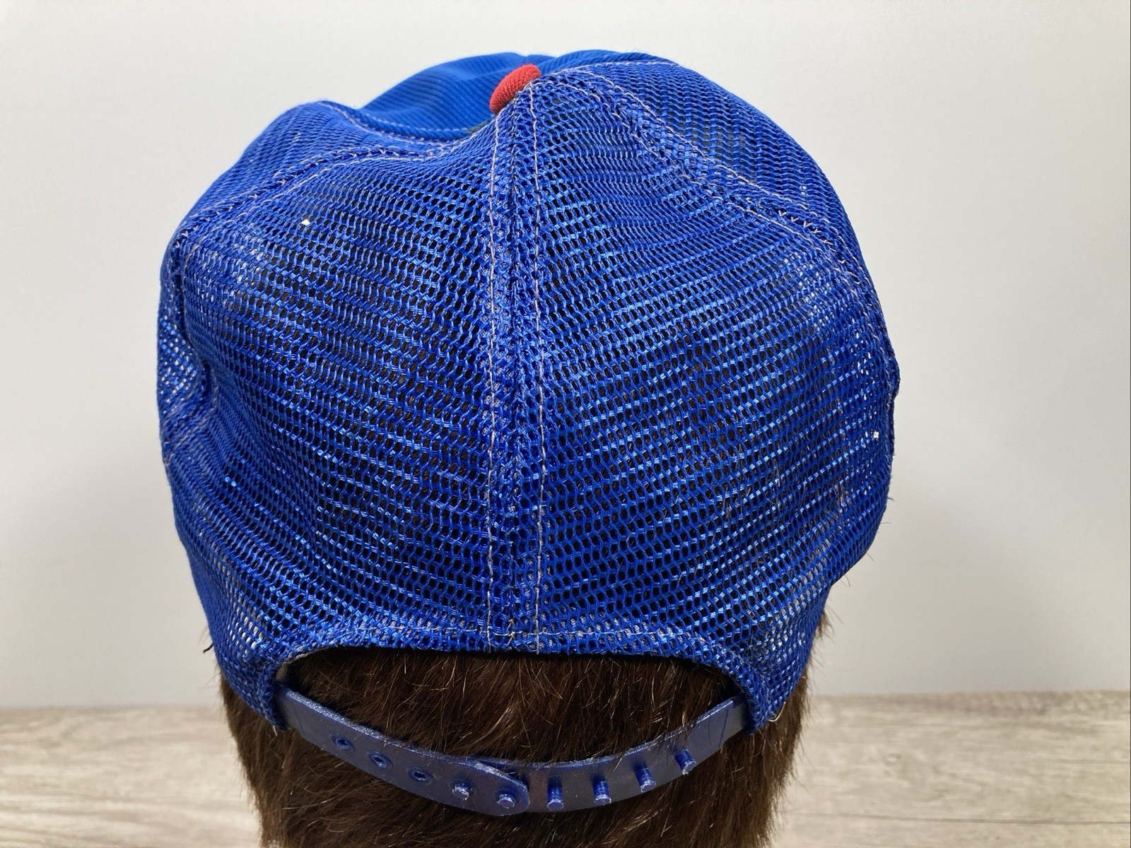 Blue US-made wide-stripe trucker hat with red cap, silver buckle, and mesh fabric on a mannequin head.