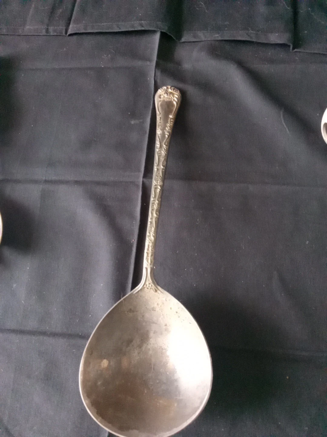 Ornate silver-plated serving ladle with floral and scrollwork handle.