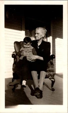 Vintage Black & White Photo Of Elderly Woman Holding Child On Porch Chair
