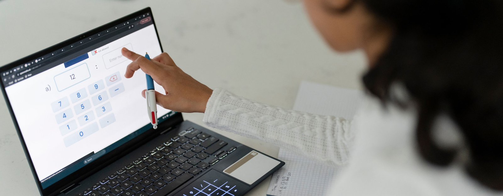 Person, die mit einem Laptop arbeitet und mathematische Berechnungen auf dem Bildschirm durchführt, während sie eine Lösung mit einem Stift zeigt.