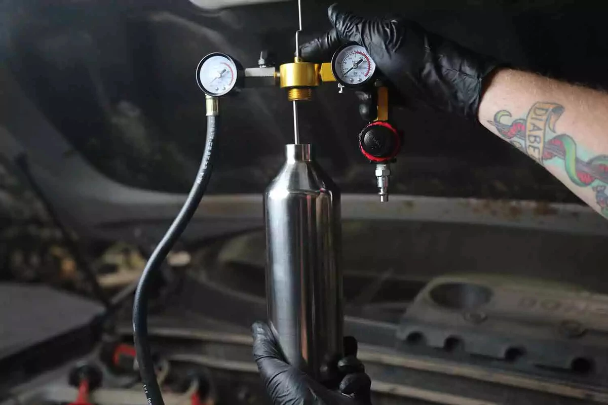 A mechanic wearing black gloves hangs the regulator from the hood.
