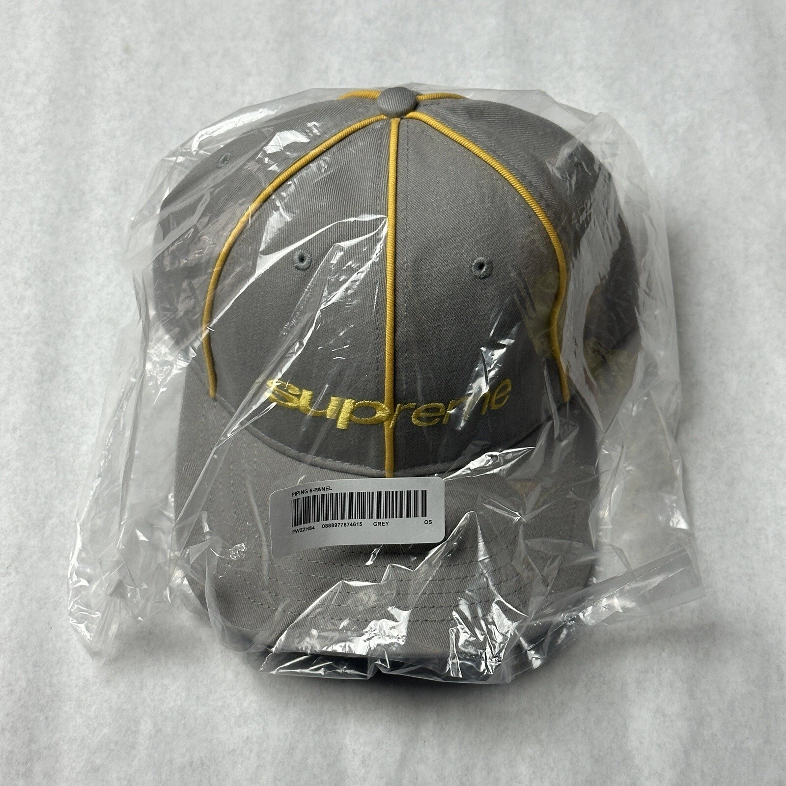 Chapeau Supreme Piping 6 panneaux FW22 NEUF dans son sac gris à la main