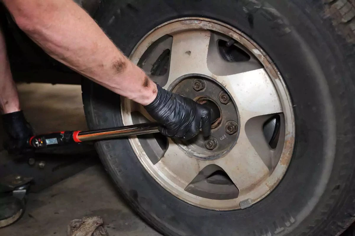 A mechanic uses a torque wrench to tighten the axle nut to factory specifications.