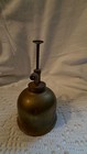 Vintage brass hand pump oiler with curved spout and long handle, made in USA, on white textured fabric background.